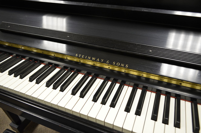 zoomed into piano keys to see the company name engraved on the wood of piano in gold text color with a gold trim along the piano keys